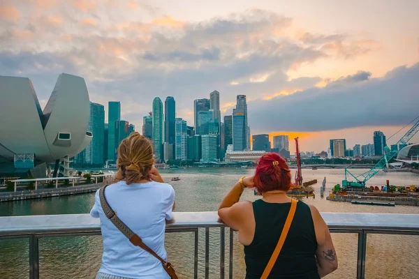 Two women standing on a bridge looking out to Marina Bay at sunset while on the 3 days in Singapore itinerary