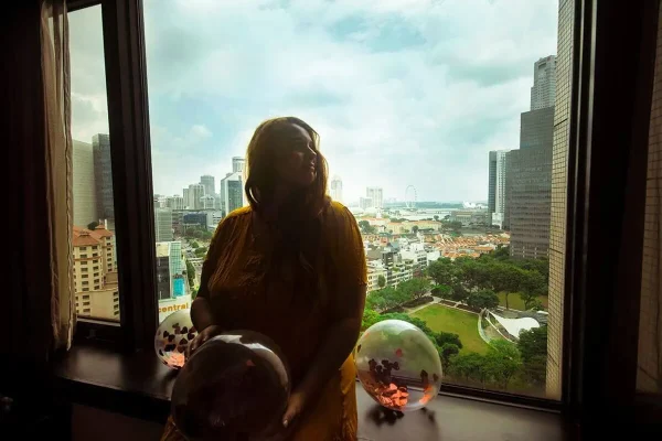 Tasha sitting by the window overlooking Singapore and the Singapore Flyer from Furama City Centre