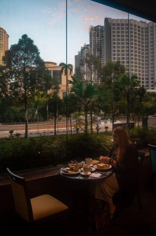 Furama RiverFront Review: What It’s Really Like To Stay Here 15 Tasha Amy eating breakfast beside the floor-to-ceiling windows at Furama RiverFront