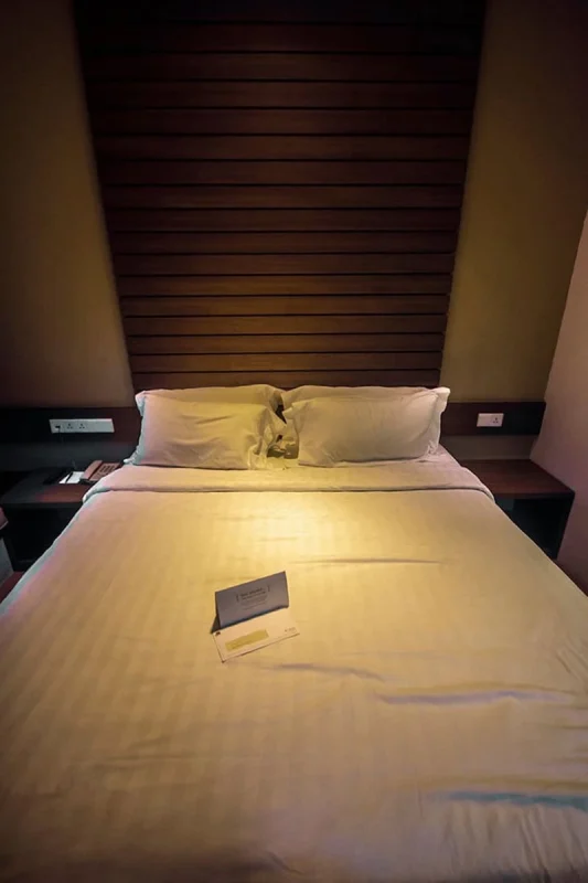 Furama RiverFront Review: What It’s Really Like To Stay Here 7 Double bed with a tall wooden feature wall inside our Furama RiverFront room