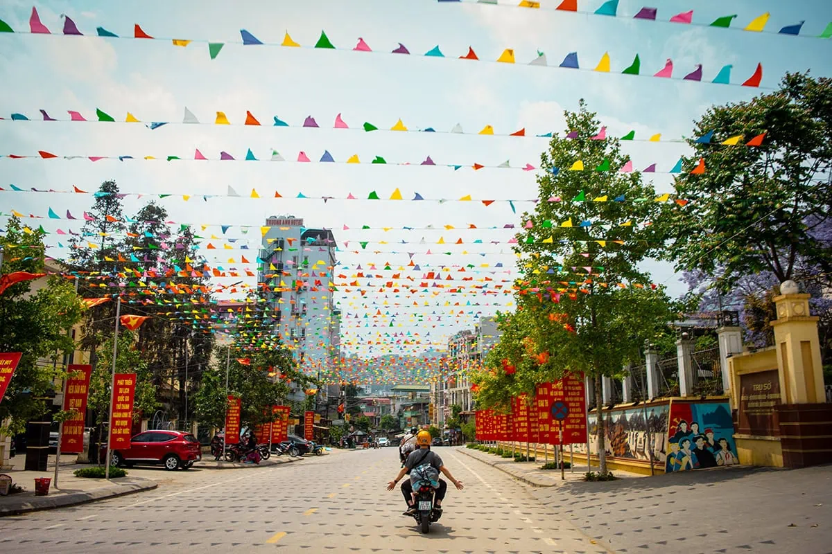 Easy Rider traveling along a street decorated with colorful flags in Meo Vac