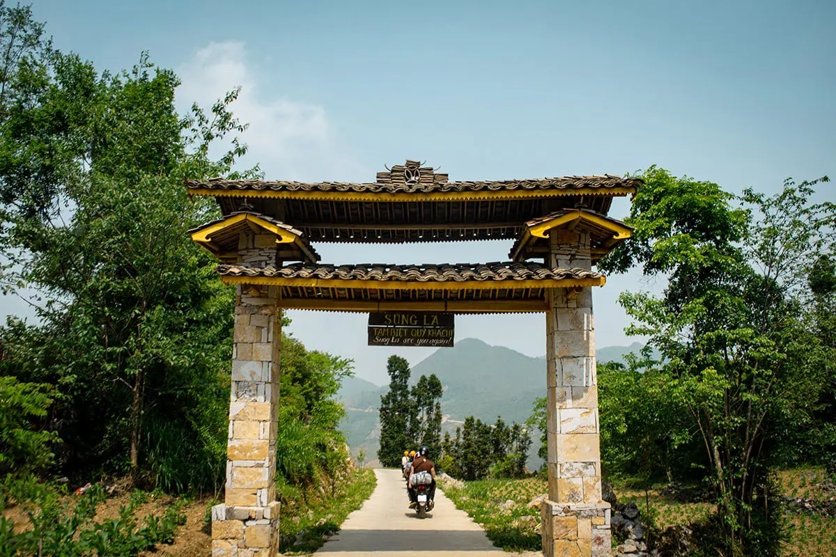 Easy Riders passing beneath the entrance gate to Sung La village