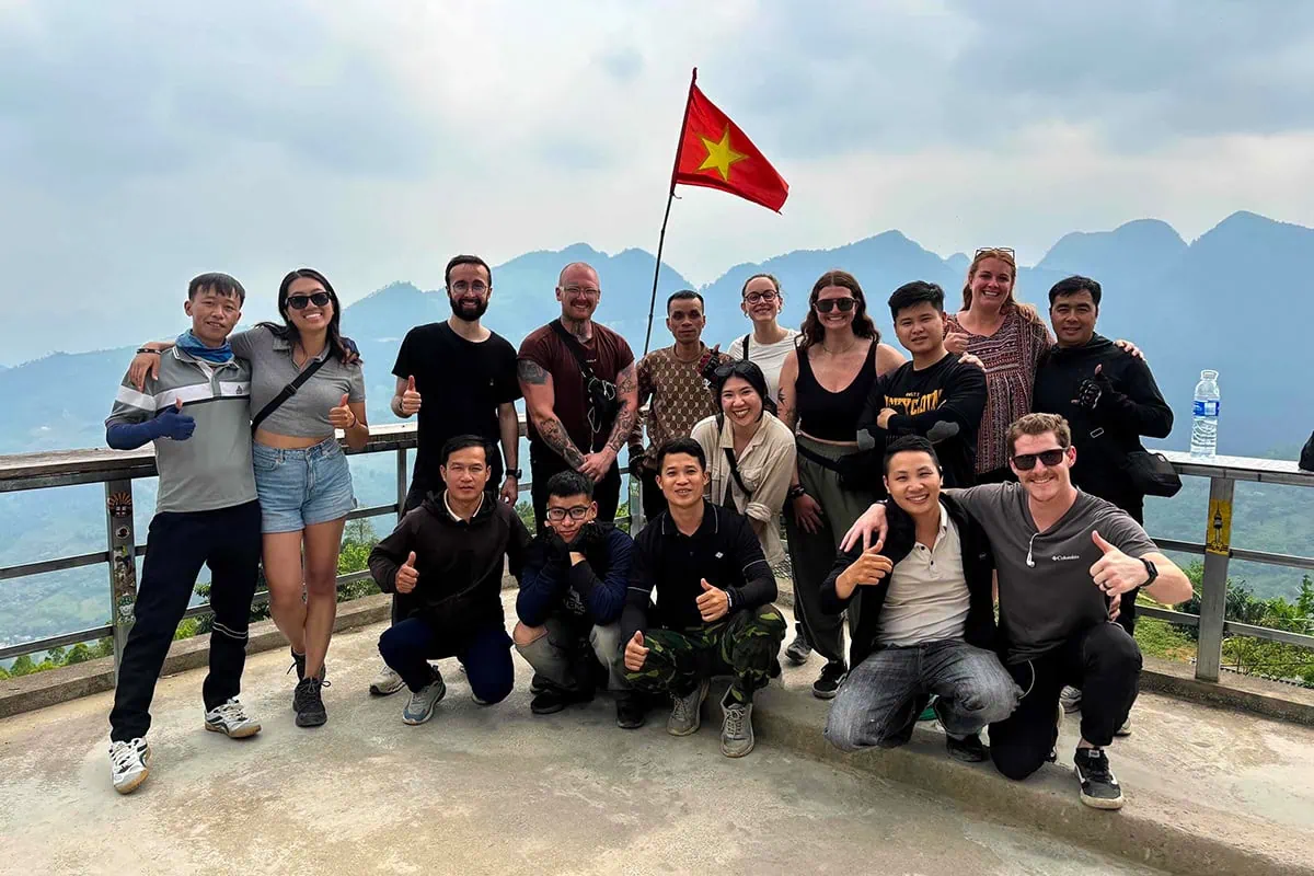 My Road Kings Ha Giang Loop group and Easy Riders posing beside a Vietnamese flag