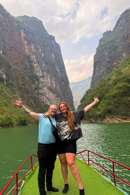 Tasha and Cory on a Nho Que River boat surrounded by steep cliffs