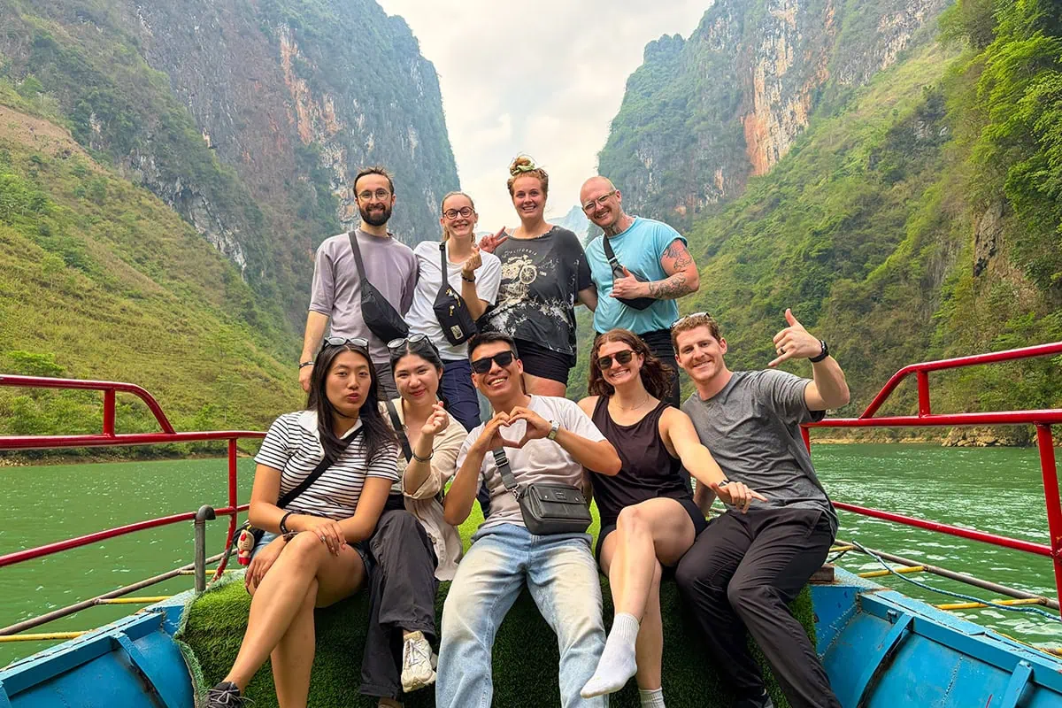Ha Giang Loop group posing on a Nho Que River boat between steep cliffs