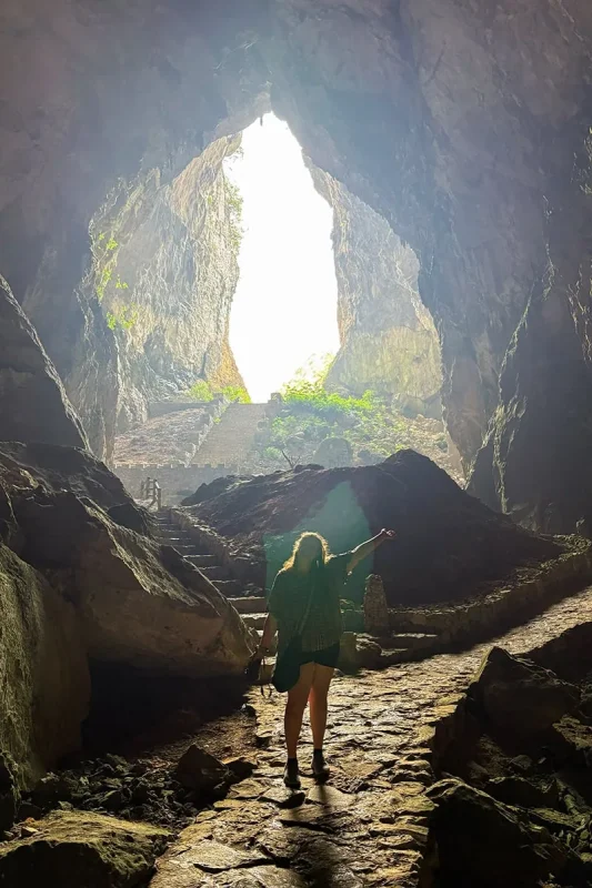 Tasha walking through Ta Lung Cave beneath a large sunlit opening