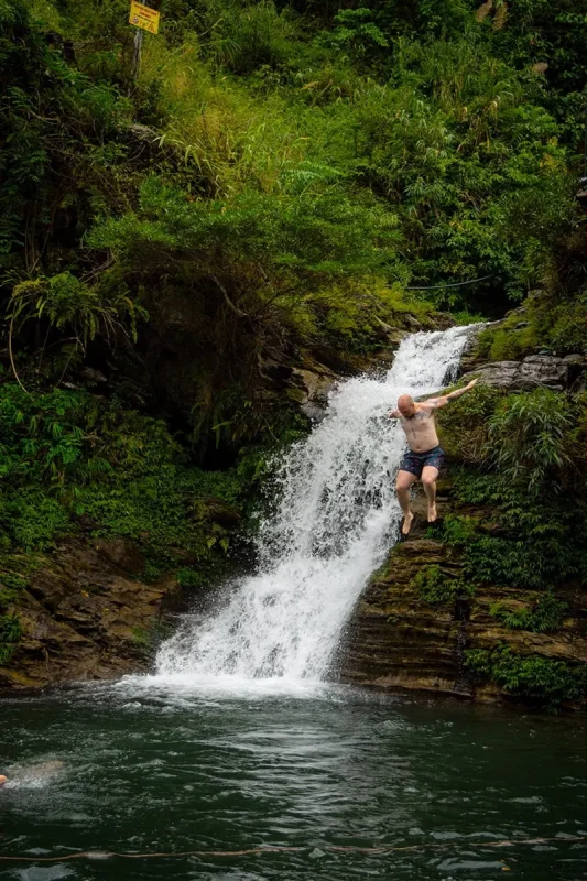Cory jumping from the rocks beside Du Gia Waterfall into the pool below