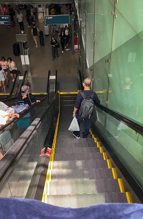 Hotel Mi Rochor Review: Is It Worth Staying Here? (2026) 30 Looking down the escalator at Singapore Airport towards the MRT