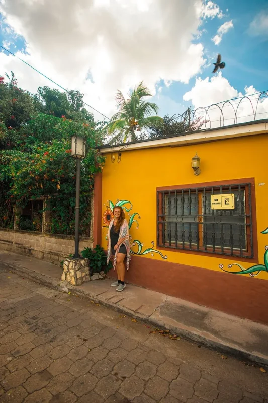 2 Weeks In Honduras Itinerary: My Recommended Route 23 Tasha standing beside a colorful yellow building in Copan Ruinas
