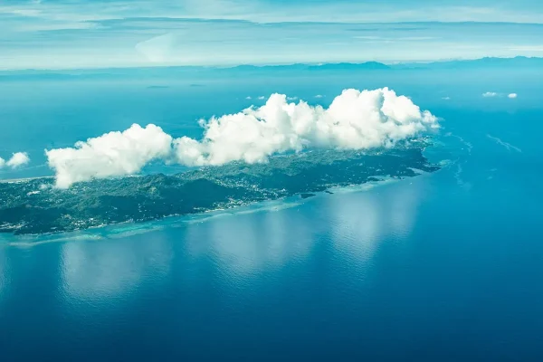 Looking down at Roatan island from above, with clouds covering part of the coastline when flying from La Ceiba to Roatan