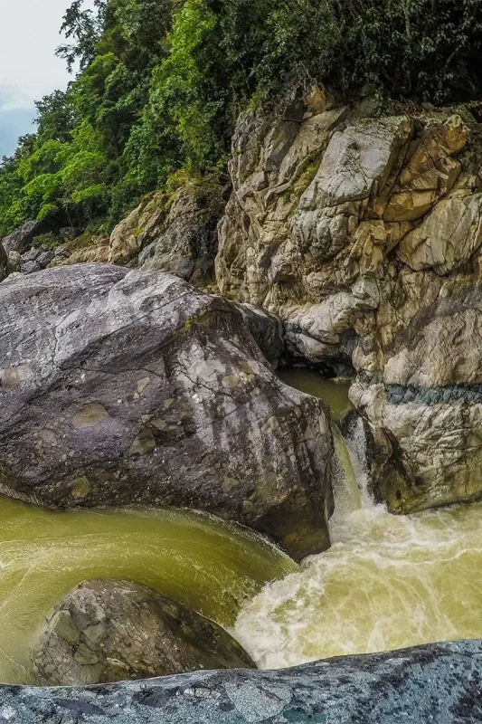 White Water Rafting In La Ceiba: My Experience On The Cangrejal River 29 Fast-flowing water passing through a narrow gap between large boulders in the Cangrejal River