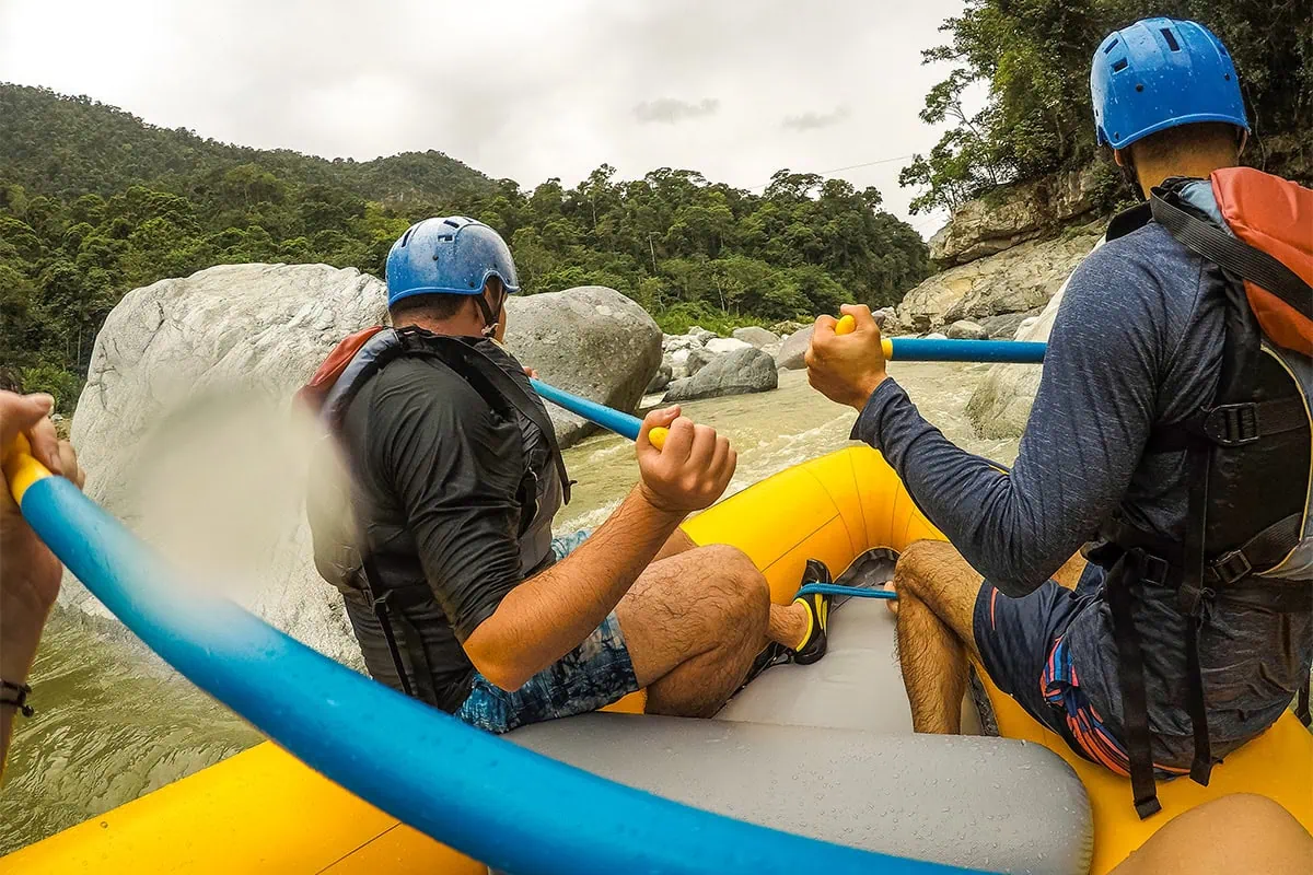 White Water Rafting In La Ceiba: My Experience On The Cangrejal River 21 Rafters navigating rapids between giant boulders while white water rafting in La Ceiba