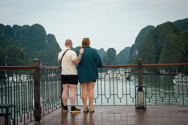 Tasha and her partner standing on Indochine Premium’s deck overlooking limestone islands and cruise boats in Ha Long Bay