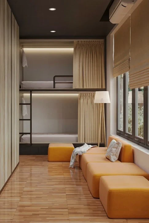 Best Hostels In Ha Giang: Where To Stay Before The Loop 60 Dorm at Bong Backpackers in Ha Giang with curtained bunk beds, a yellow sofa and large windows