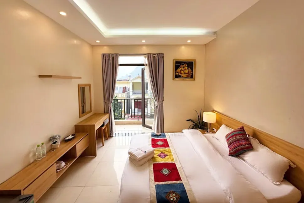 Best Hostels In Ha Giang: Where To Stay Before The Loop 65 Private double room at Hong Hao Hostel in Ha Giang with a wooden bed, desk and doors opening onto a balcony