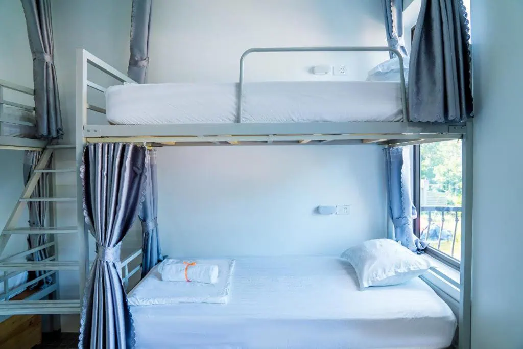 Best Hostels In Ha Giang: Where To Stay Before The Loop 64 Dorm bunk beds at Lila Inn in Ha Giang with gray privacy curtains, reading lights and power sockets beside a window