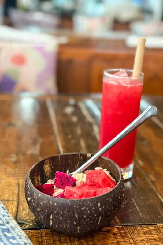Best Hostels In Ha Giang: Where To Stay Before The Loop 70 Coconut-shell bowl of watermelon and dragon fruit beside a watermelon juice at Top Of The Loop Hostel