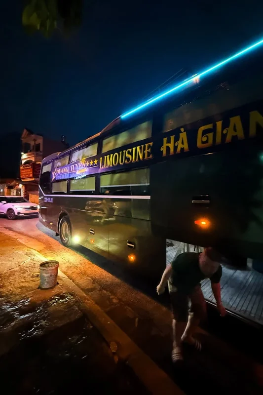 Ha Giang To Ha Long Bay: My VIP Sleeper Bus Experience (2026) 70 A green sleeper bus parked beside the road at night with its luggage compartment open