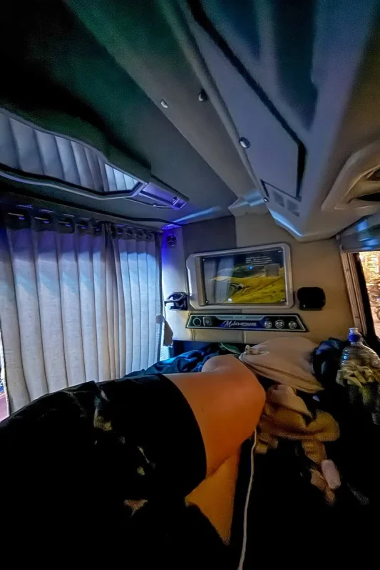 Ha Giang To Ha Long Bay: My VIP Sleeper Bus Experience (2026) 65 View inside a sleeper bus cabin showing a screen, pillow, blanket and privacy curtain