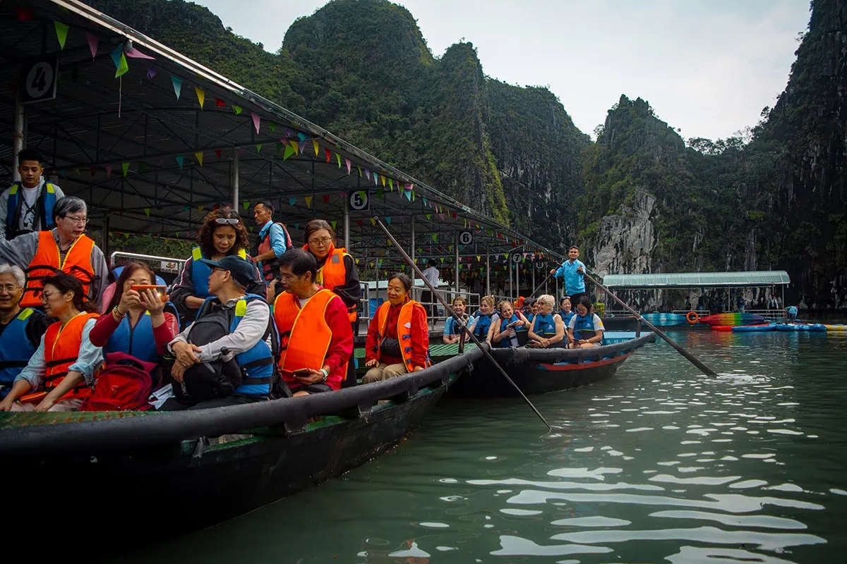 Luon Cave Ha Long Bay: Is It Worth Visiting? 68 Visitors wearing life jackets in wooden rowboats beside the covered boarding area at Luon Cave