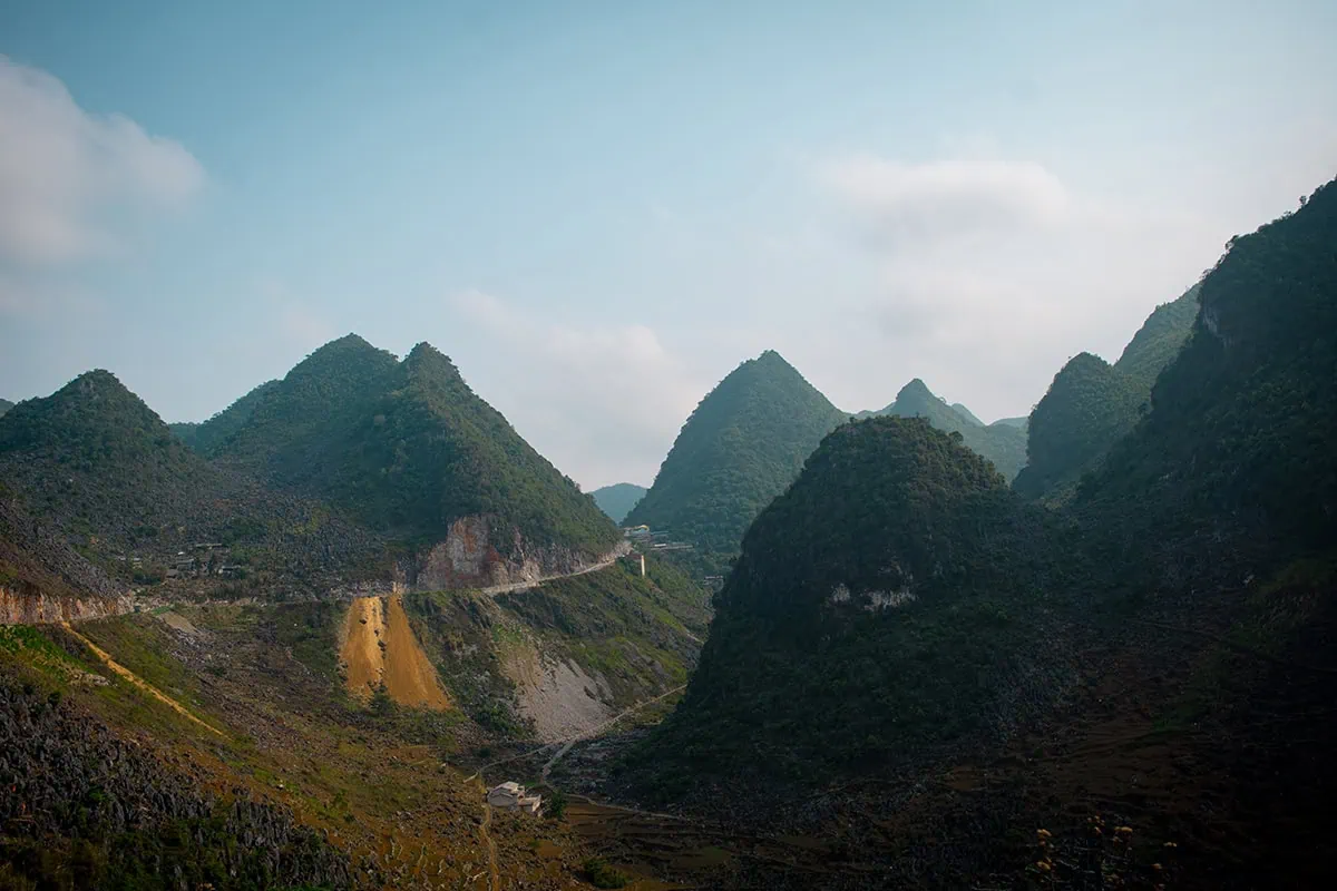 A winding mountain road passing through jagged limestone peaks near Dong Van