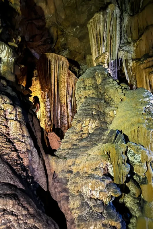 Large flowstone formations illuminated by phone lights inside Ta Lung Cave in Ha Giang