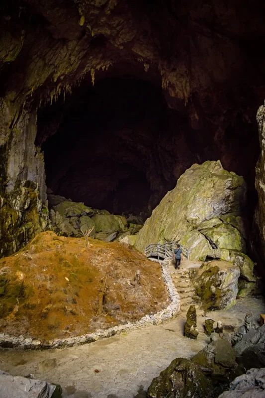 A traveler crossing a small bridge between giant rocks inside Ta Lung Cave
